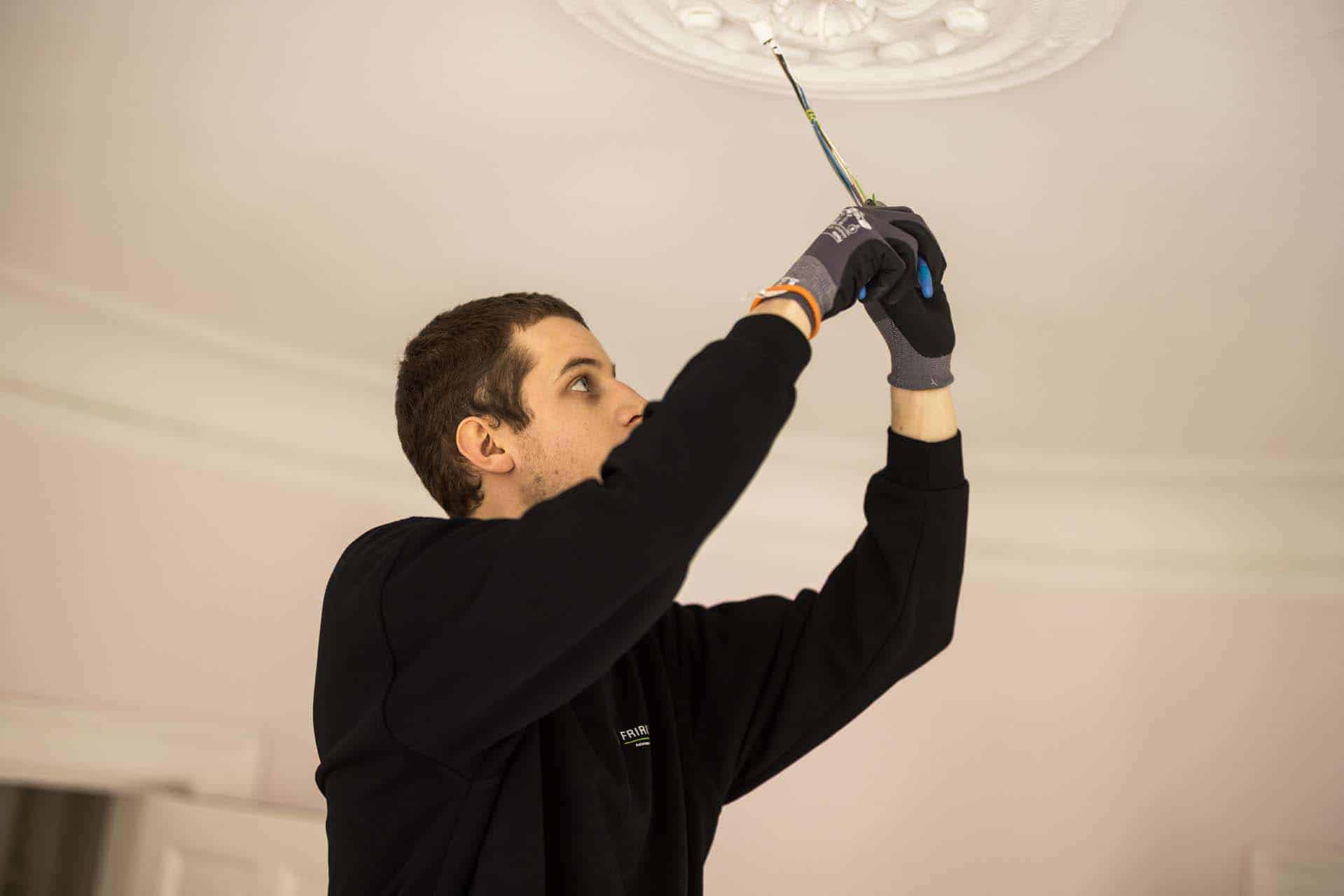 Elektriker arbejder på ledninger til loftslampe